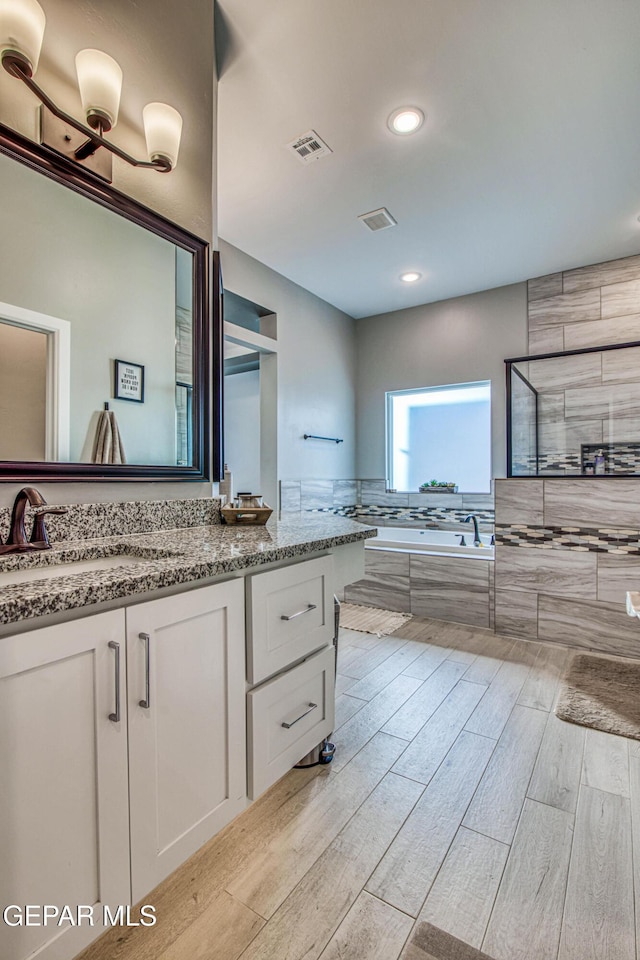 bathroom with separate shower and tub, hardwood / wood-style floors, and vanity