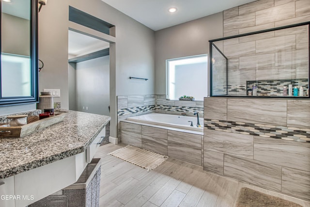 bathroom featuring hardwood / wood-style floors, vanity, and separate shower and tub