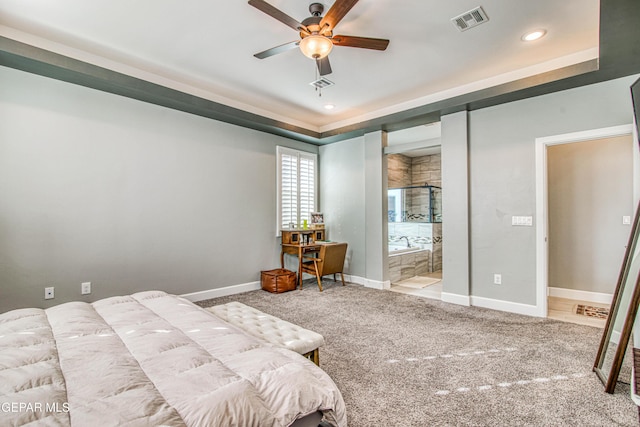 bedroom with light carpet, ensuite bathroom, ceiling fan, and a tray ceiling