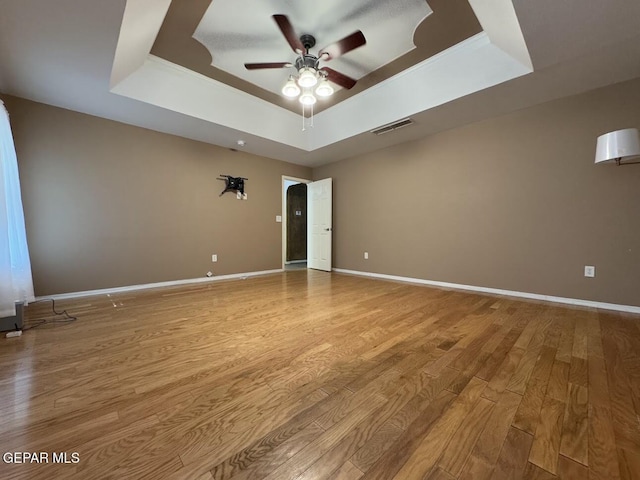 spare room featuring a tray ceiling, ceiling fan, and light hardwood / wood-style floors