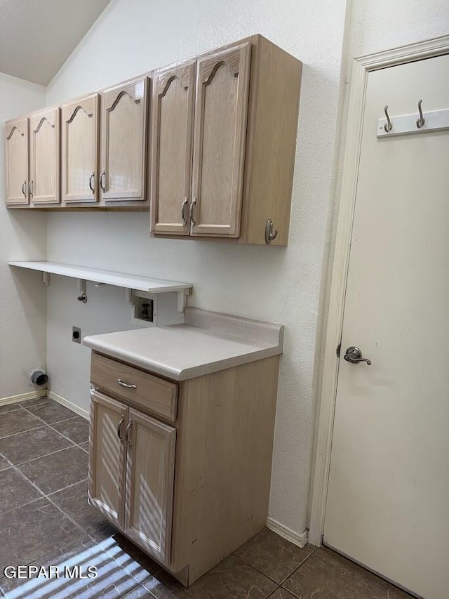 laundry area with electric dryer hookup, cabinets, and dark tile patterned floors