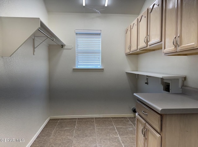 laundry area featuring cabinets and dark tile patterned floors