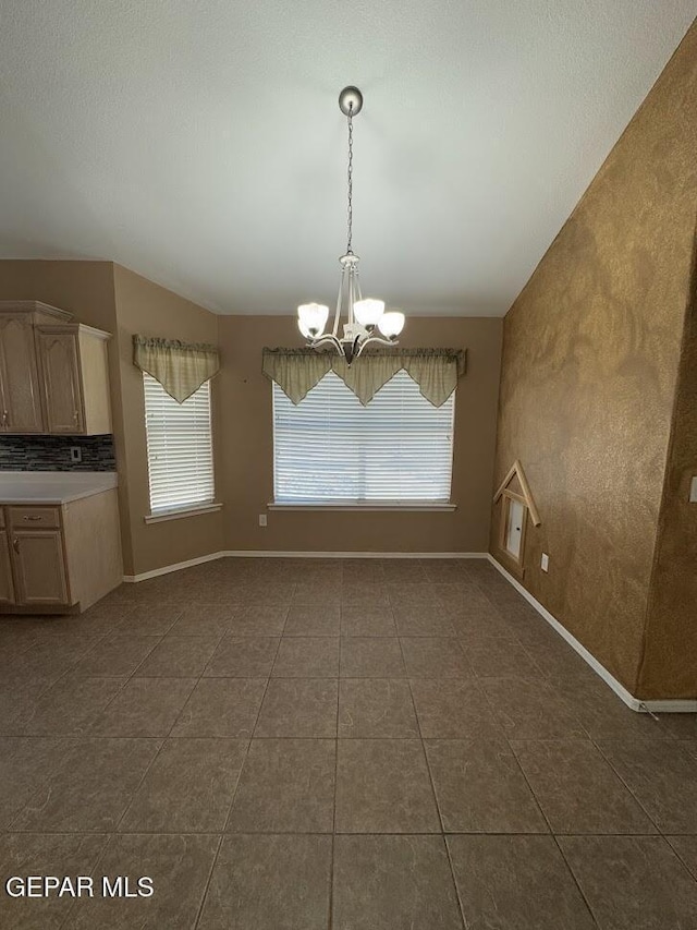 unfurnished dining area featuring a chandelier and dark tile patterned floors