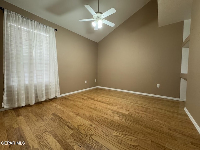 spare room with light hardwood / wood-style flooring, vaulted ceiling, and ceiling fan