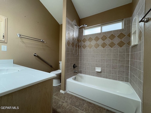 full bathroom featuring vanity, tile patterned floors, tiled shower / bath, vaulted ceiling, and toilet