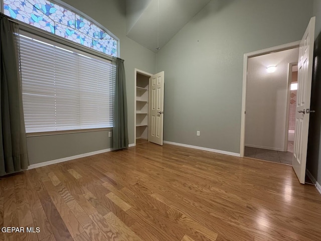 unfurnished bedroom with light hardwood / wood-style floors and high vaulted ceiling