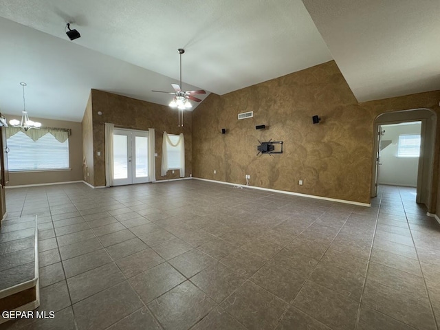 tiled empty room featuring high vaulted ceiling and ceiling fan with notable chandelier