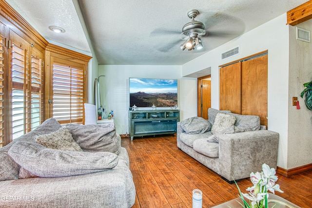 living room featuring ceiling fan, dark hardwood / wood-style floors, and a textured ceiling