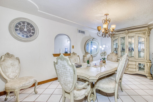 tiled dining room featuring a notable chandelier and a textured ceiling