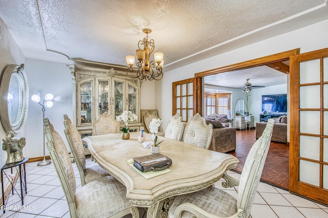 tiled dining space featuring a textured ceiling, french doors, and ceiling fan with notable chandelier