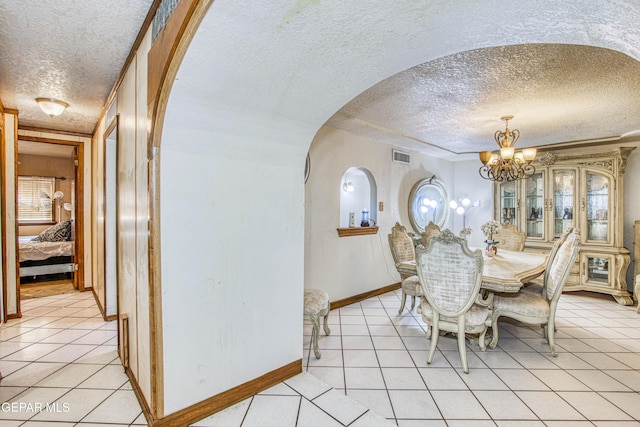 dining area featuring a notable chandelier, light tile patterned floors, and a textured ceiling