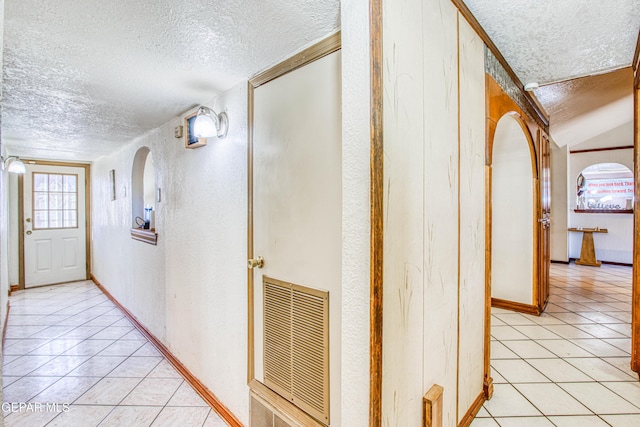 corridor featuring light tile patterned floors and a textured ceiling