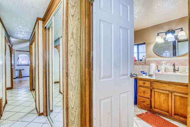 bathroom with tile patterned floors, decorative backsplash, a textured ceiling, and vanity