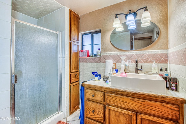 bathroom with vanity, an enclosed shower, and tile walls