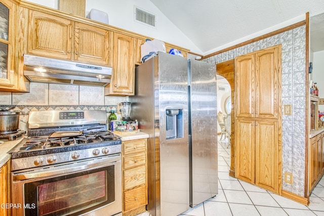 kitchen with decorative backsplash, stainless steel appliances, vaulted ceiling, and light tile patterned flooring