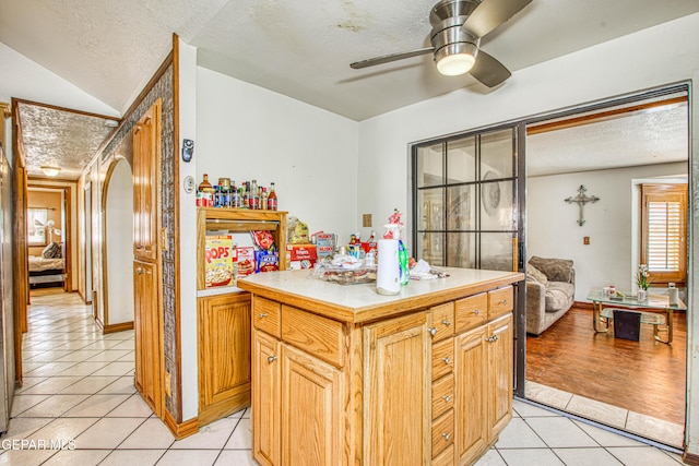 kitchen featuring a center island, lofted ceiling, ceiling fan, a textured ceiling, and light tile patterned flooring