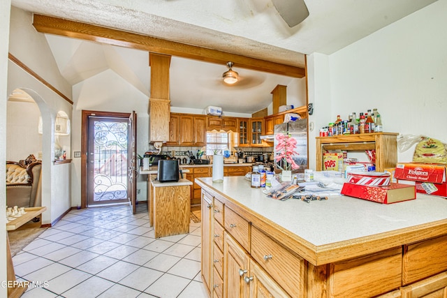 kitchen featuring light tile patterned floors, a center island, ceiling fan, and vaulted ceiling with beams