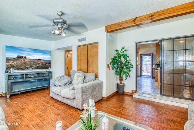 living room with ceiling fan, dark hardwood / wood-style flooring, and a textured ceiling