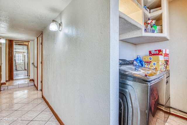 interior space with light tile patterned flooring, a textured ceiling, and washer / clothes dryer