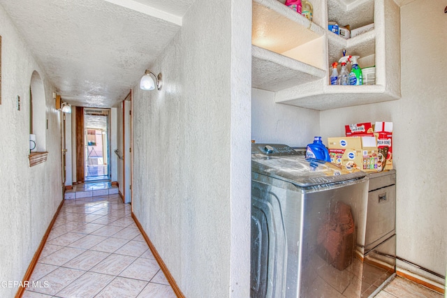 corridor with light tile patterned floors, a textured ceiling, and independent washer and dryer