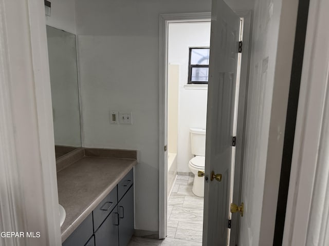 bathroom featuring vanity, toilet, and a washtub