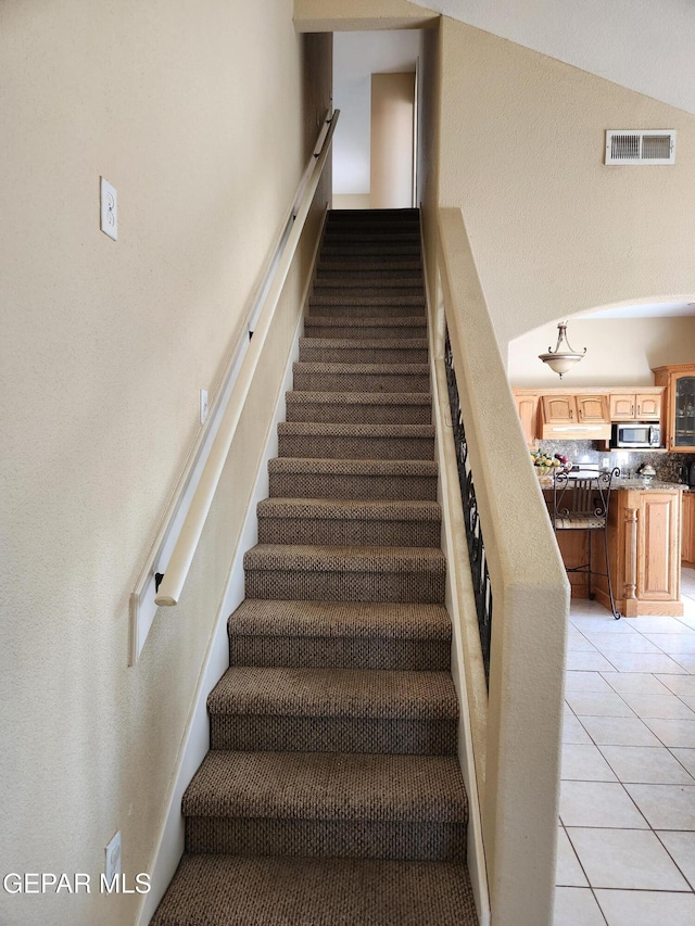 stairs with tile patterned flooring and vaulted ceiling