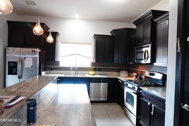 kitchen with sink, decorative light fixtures, light tile patterned floors, appliances with stainless steel finishes, and backsplash