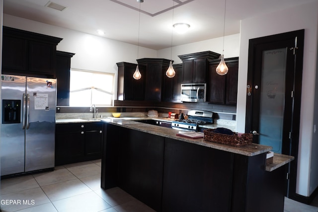 kitchen featuring appliances with stainless steel finishes, hanging light fixtures, a center island, tasteful backsplash, and light tile patterned flooring