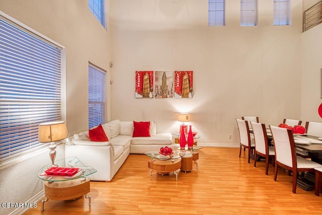 living room featuring light wood-type flooring and a towering ceiling