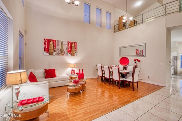 living room with wood-type flooring, high vaulted ceiling, and a notable chandelier