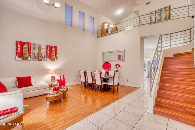 living room featuring hardwood / wood-style flooring, high vaulted ceiling, and an inviting chandelier