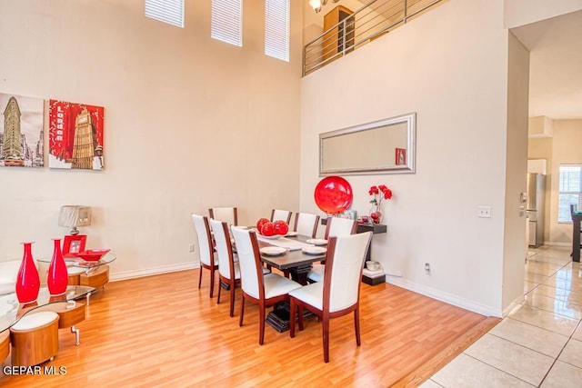 dining area with hardwood / wood-style floors and a towering ceiling