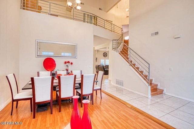 dining area with hardwood / wood-style floors, a high ceiling, and an inviting chandelier