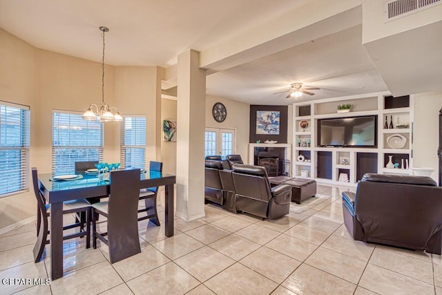 tiled dining space with ceiling fan with notable chandelier and built in features