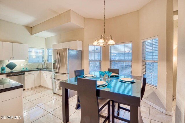 tiled dining area featuring a high ceiling, an inviting chandelier, a wealth of natural light, and sink