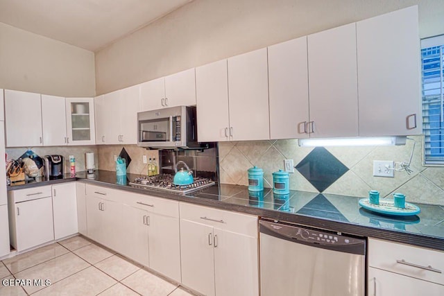 kitchen featuring white cabinets, light tile patterned floors, stainless steel appliances, and tasteful backsplash