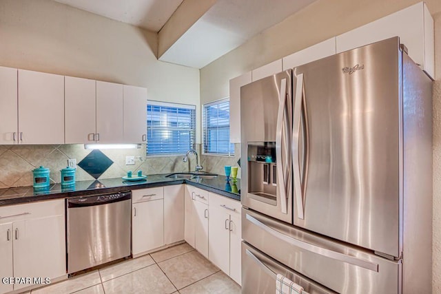 kitchen with decorative backsplash, appliances with stainless steel finishes, sink, light tile patterned floors, and white cabinets