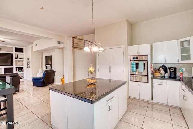 kitchen with white cabinets, oven, light tile patterned floors, and an inviting chandelier