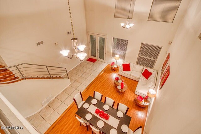 living room with a high ceiling, tile patterned floors, french doors, and a notable chandelier