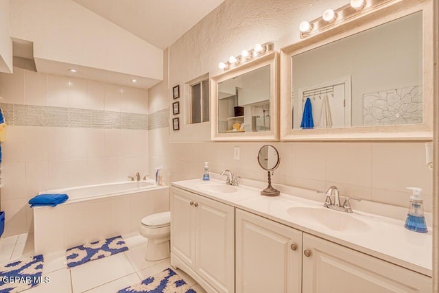 bathroom featuring tile patterned floors, vanity, vaulted ceiling, toilet, and a bathing tub