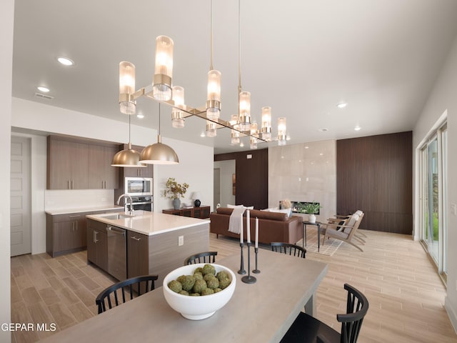 dining space with a notable chandelier, light wood-type flooring, and sink