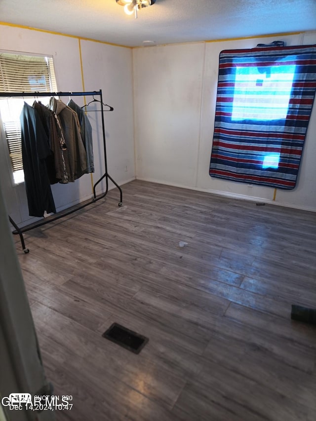 unfurnished room with dark hardwood / wood-style flooring and a textured ceiling