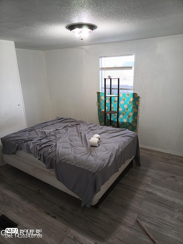 bedroom featuring dark hardwood / wood-style flooring and a textured ceiling