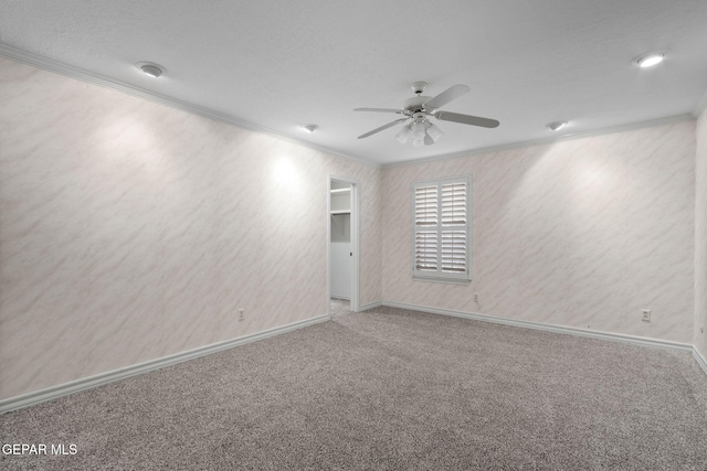 empty room featuring baseboards, carpet, ornamental molding, and a ceiling fan