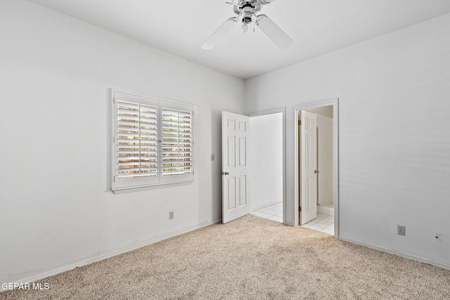 unfurnished bedroom with light tile patterned floors, a ceiling fan, baseboards, light carpet, and connected bathroom