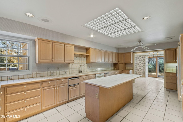 kitchen with light brown cabinetry, a sink, a center island, light tile patterned floors, and decorative backsplash