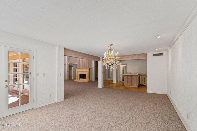 unfurnished living room featuring light carpet, visible vents, a fireplace with raised hearth, and a textured ceiling