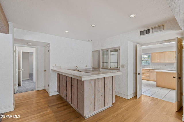 kitchen with light wood-type flooring, visible vents, light brown cabinetry, and light countertops