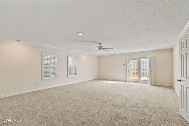 carpeted empty room with a wealth of natural light, a textured ceiling, a ceiling fan, and ornamental molding