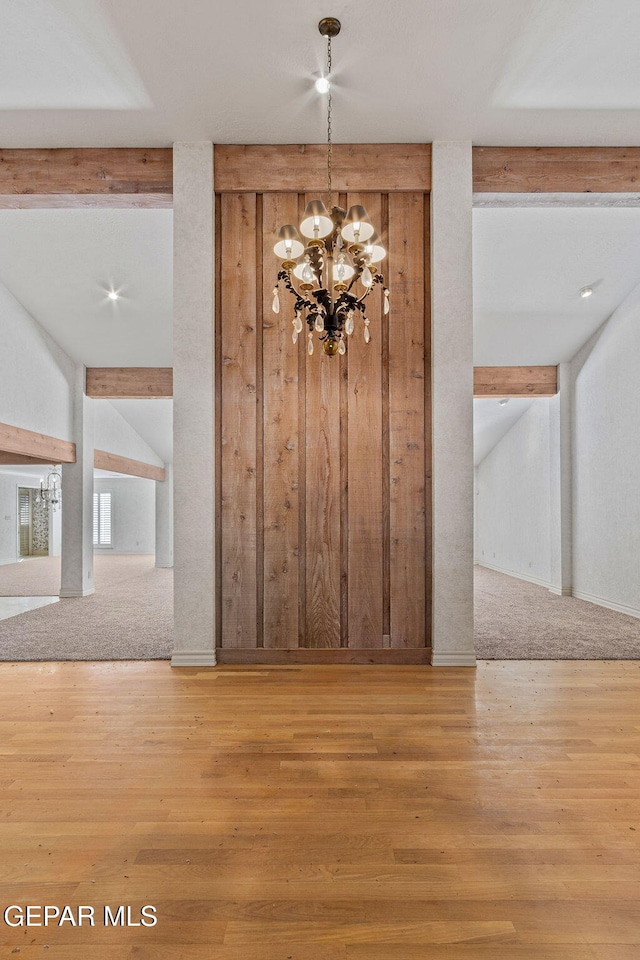 interior space with lofted ceiling with beams, a notable chandelier, and wood finished floors